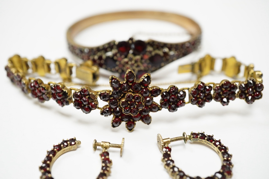 Three items of gilt white metal and garnet paste cluster set jewellery, comprising a bracelet, bangle and pair of Czechoslovakian earrings. Condition - fair